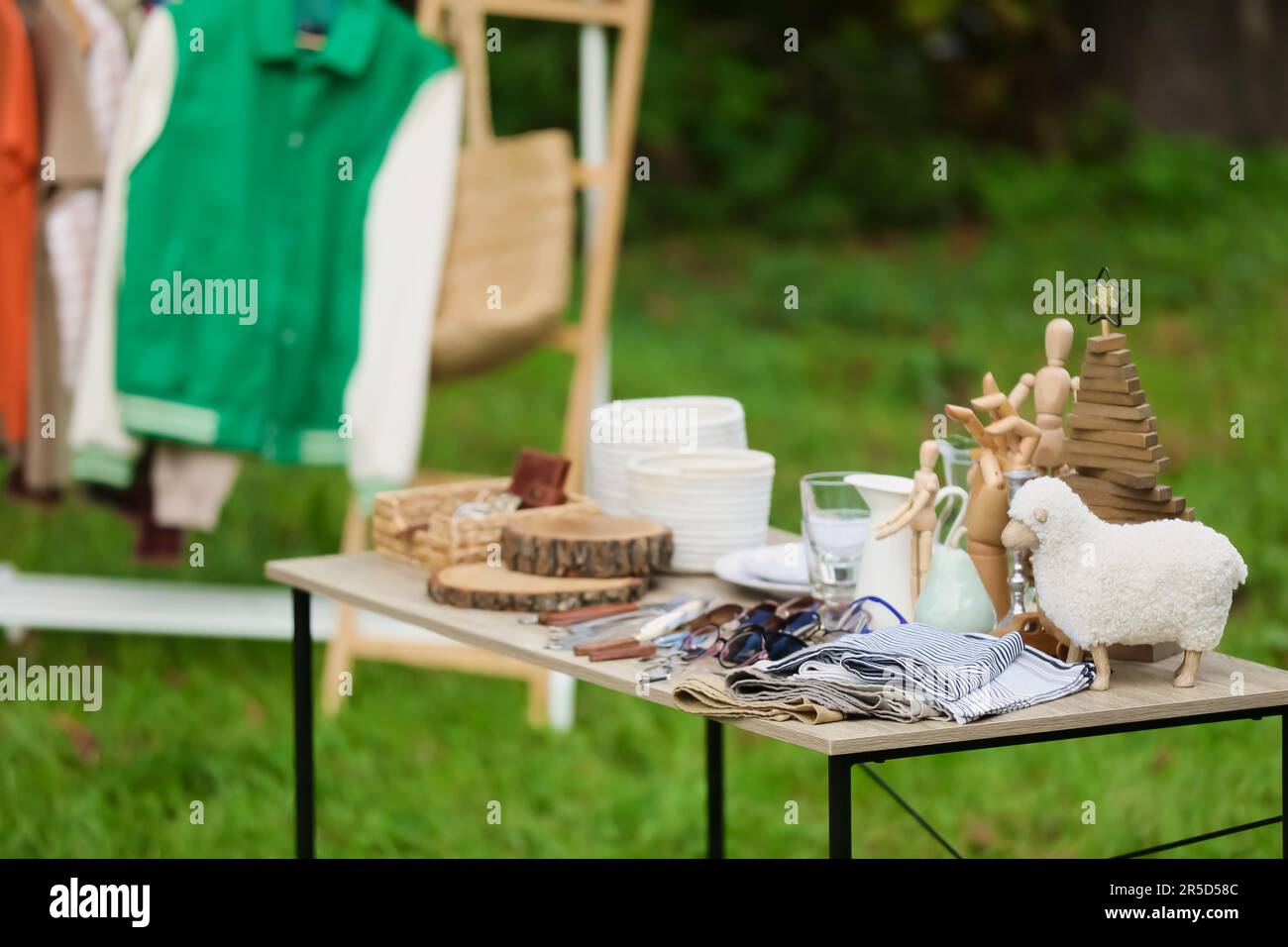 Kleiderständer und kleiner Tisch mit verschiedenen Gegenständen im Freien. Garagenverkauf Stockfoto