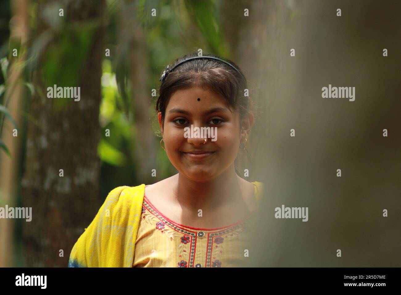 Nahaufnahme eines indischen Teenagers, das über den Naturhintergrund in die Kamera schaut. Stockfoto