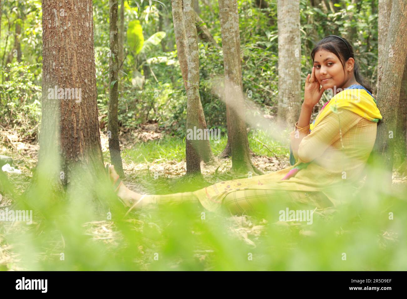 Nahaufnahme eines indischen Teenagers, das über den Naturhintergrund in die Kamera schaut. Stockfoto