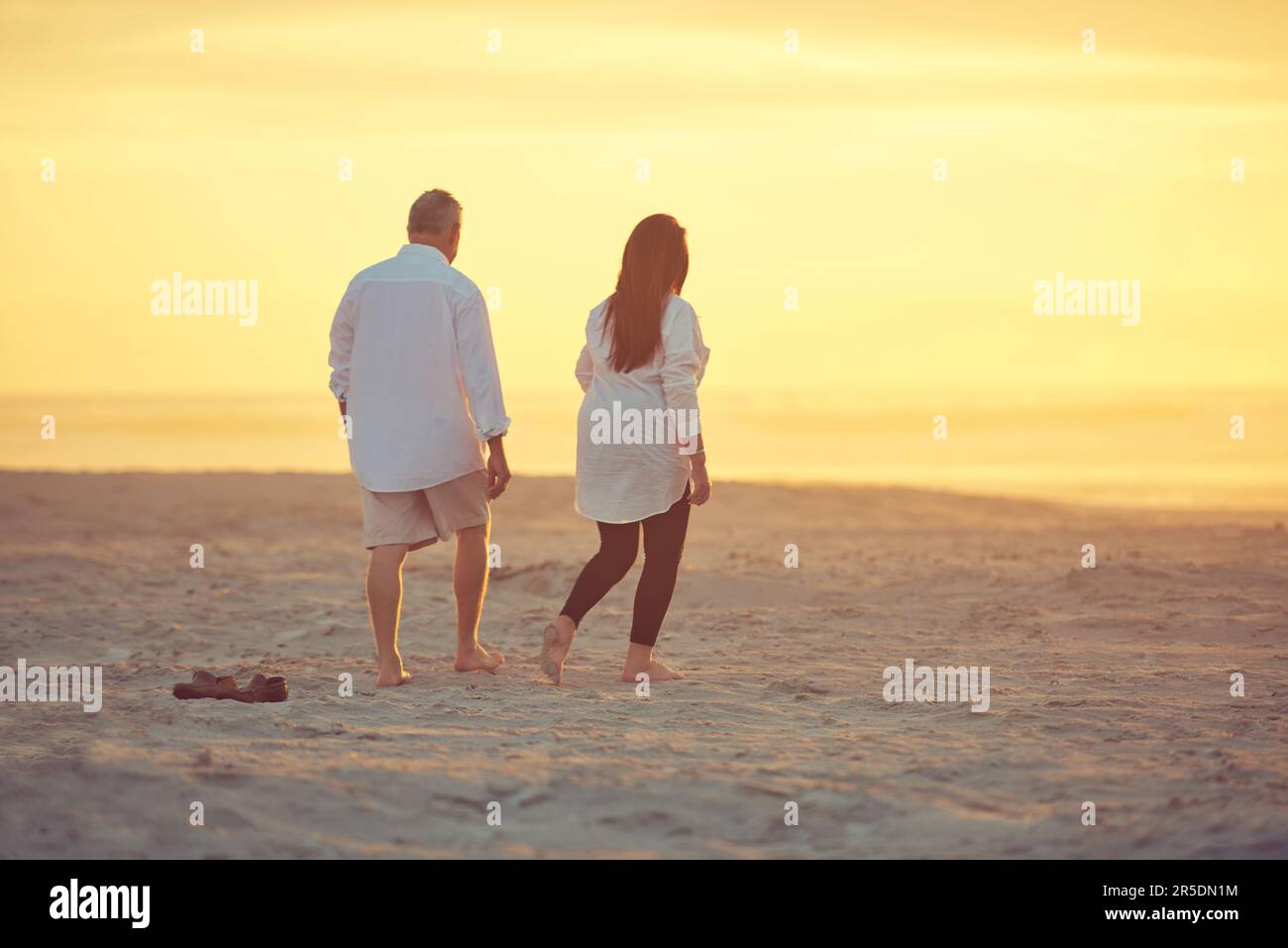 Manchmal muss man einfach fliehen. Ein reifes Paar, das einen entspannenden Spaziergang am Strand macht. Stockfoto