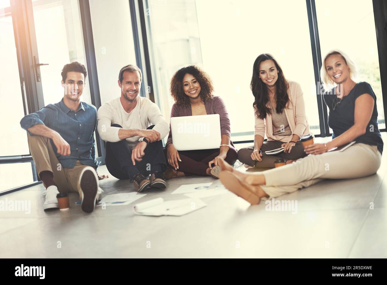 Innovation ist der Katalysator für den Erfolg unserer Teams. Porträt eines Teams von Designern, die im Büro ein Brainstorming auf dem Boden durchführen. Stockfoto