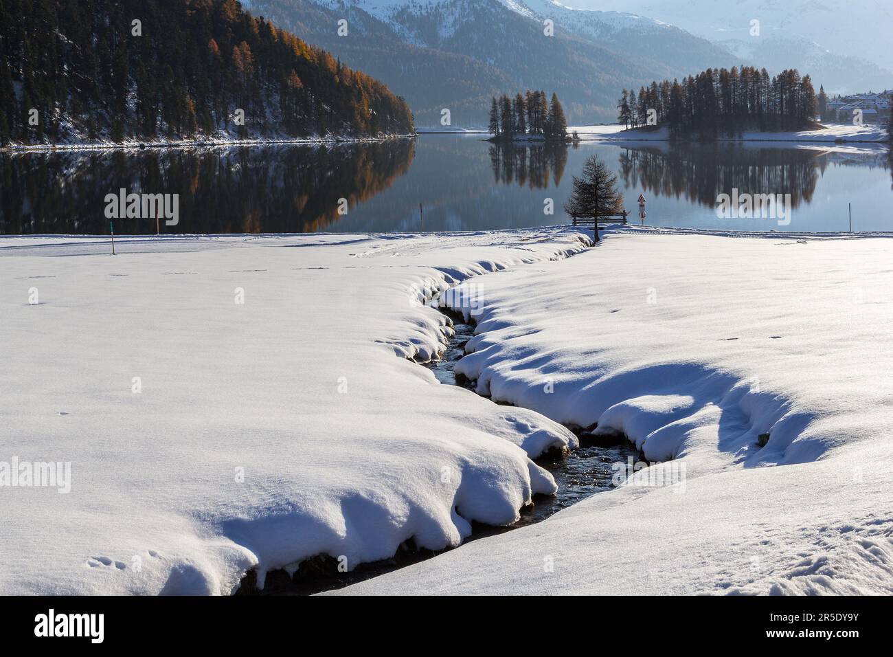 Der kurvige Bach, der zum See fließt, ist im Winter mit tiefem Schnee bedeckt Stockfoto
