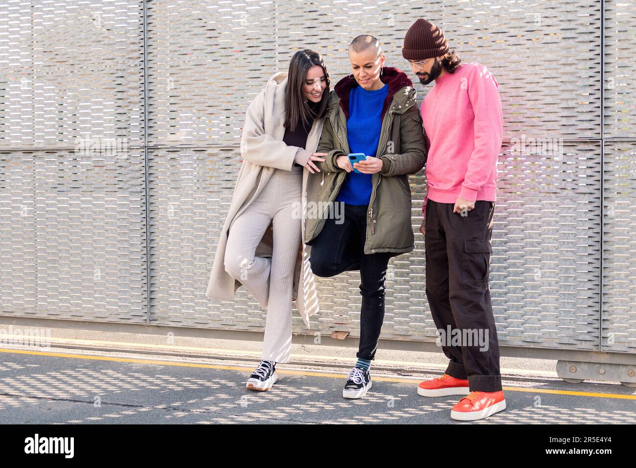 Drei glückliche junge Freunde, die gerne telefonieren Stockfoto