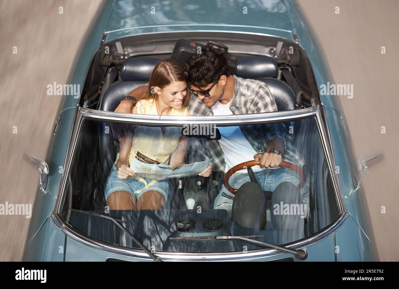 Unser lustiger Tag im Sportwagen. Zugeschnittenes Bild eines jungen Paares, das in einem offenen Sportwagen sitzt. Stockfoto
