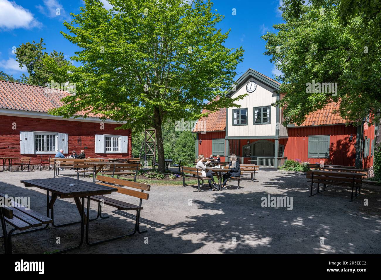 An einem sonnigen Tag Anfang Juni 2023 genießen die Menschen im Färgargården entlang des Flusses Motala in Norrköping einen Kaffee. Stockfoto