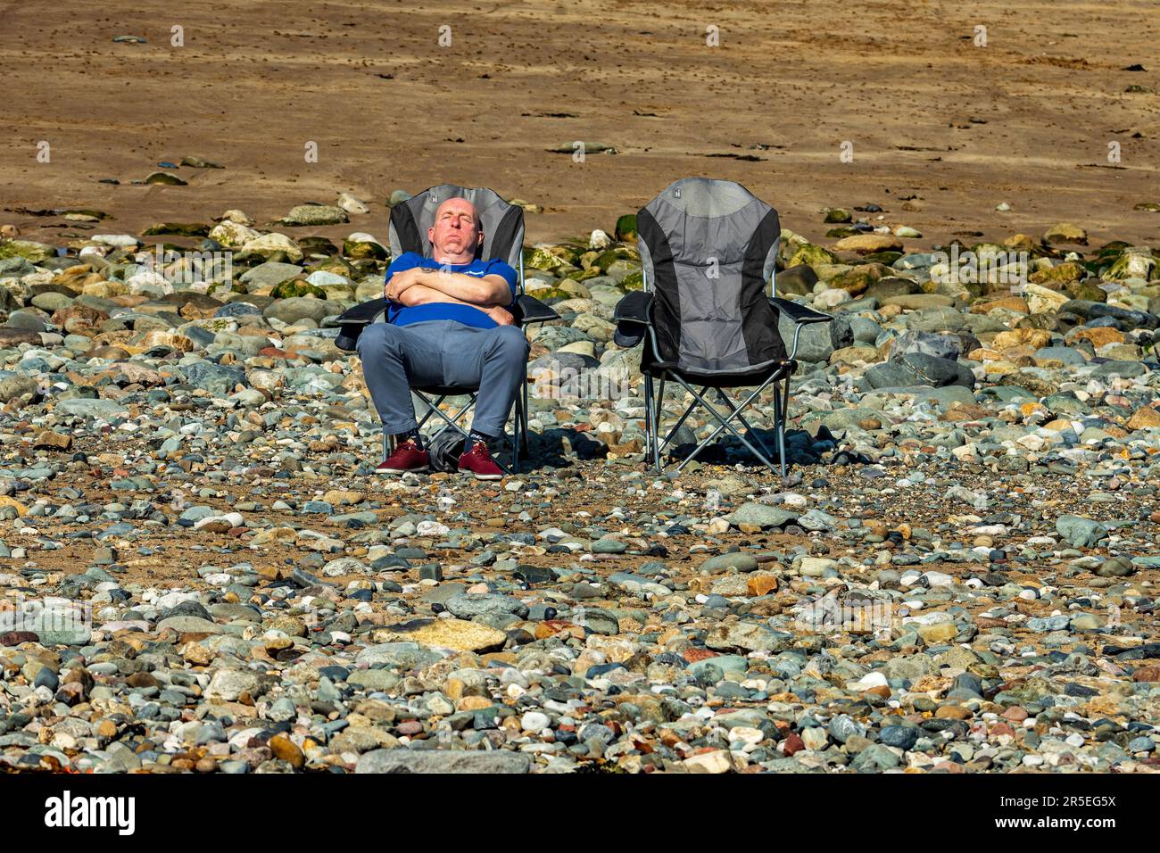 Einsamer männlicher Urlauber, der sich an einem steinigen Strand entspannen und sonnen kann. Stockfoto