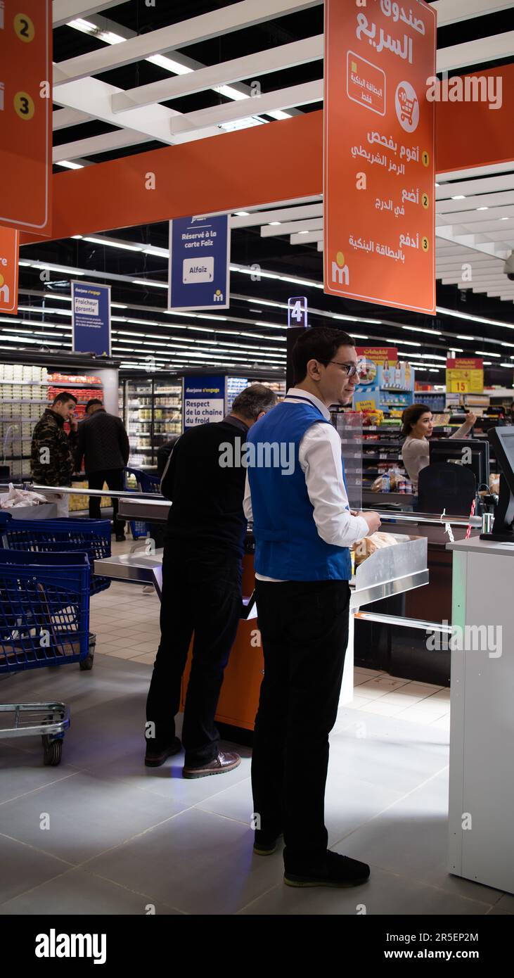 Mitarbeiter unterstützen Kunden beim Navigieren an der Kasse im Supermarkt Stockfoto