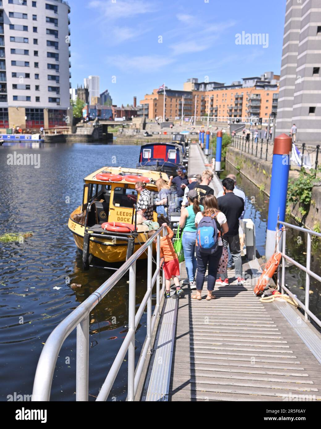Leeds, West Yorkshire, Vereinigtes Königreich, 3. Juni 2023. Leute, die in der heißen Nachmittagssonne am Leeds Dock Schlange stehen, um an Bord eines Taxiboots zu gehen. Kredit: Paul Biggins/Alamy Live News Stockfoto