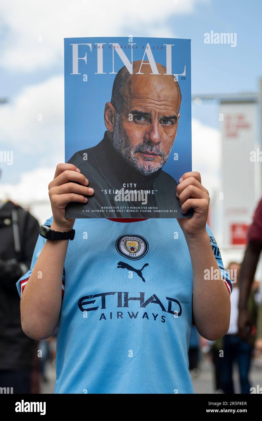 London, Großbritannien. 3. Juni 2023 Ein Manchester City-Fan hält das offizielle Programm ab, mit Manager Pep Guardiola auf dem Cover, vor dem FA-Cup-Finale zwischen Manchester City und Manchester United im Wembley Stadium. Aus Gründen der Sicherheit der Menschenmenge wurde in diesem Gebiet ein Alkoholverbot verhängt. Kredit: Stephen Chung / Alamy Live News Stockfoto