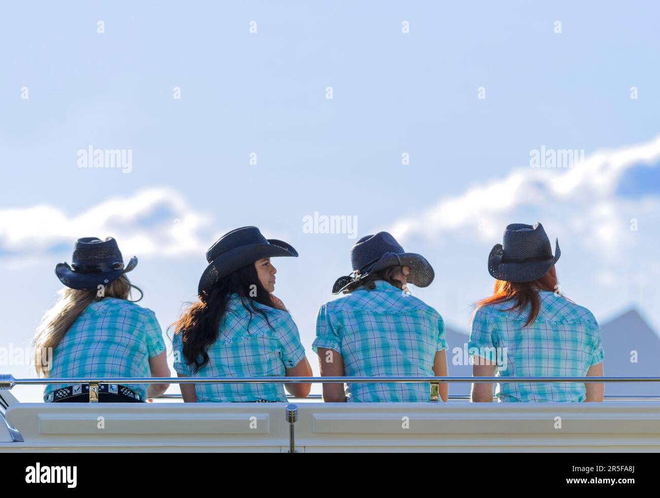 Vier Cowgirls mit schwarzen Cowboyhüten, die die Calgary Stampede Parade sehen Stockfoto