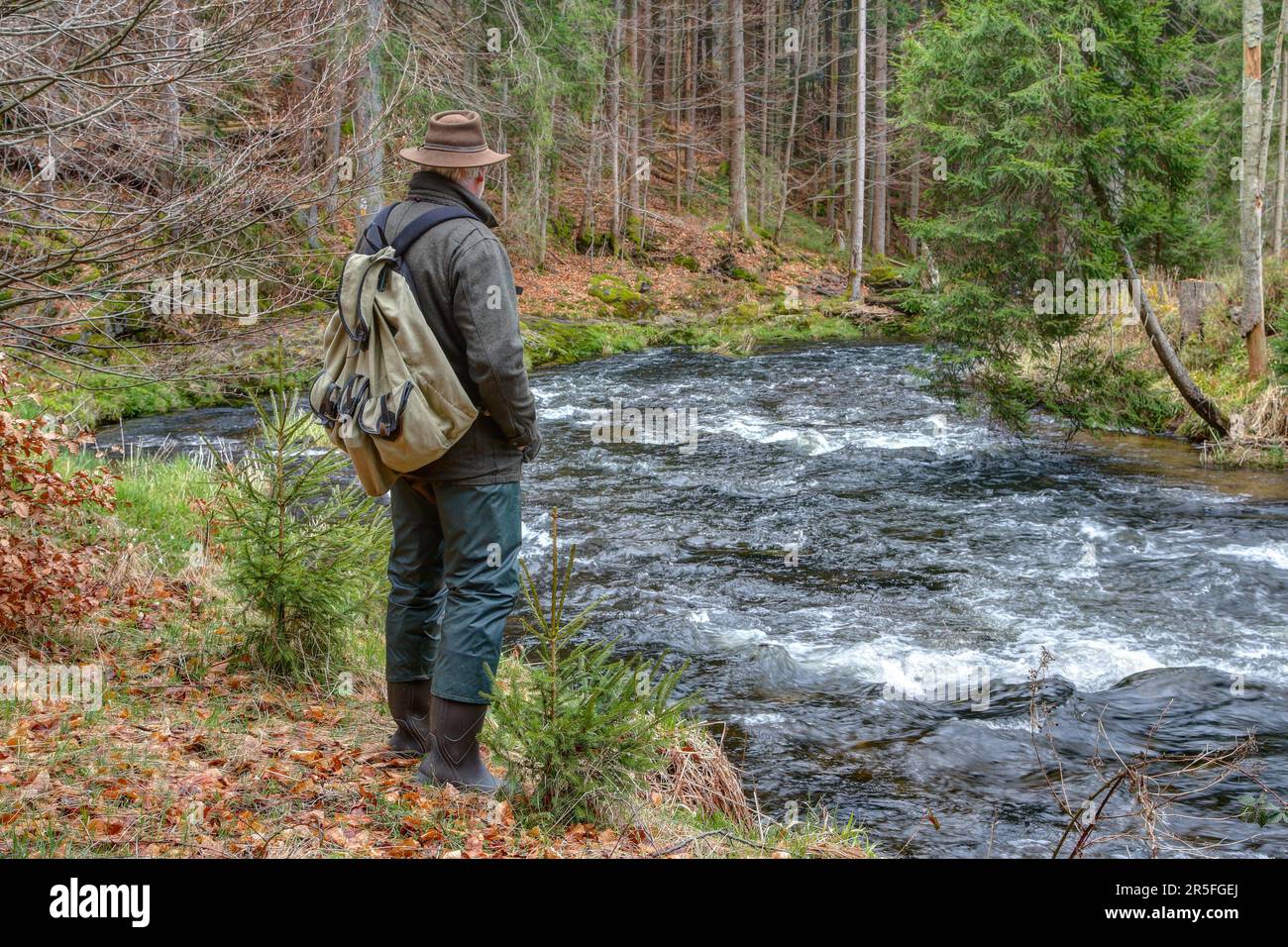 Ein Wanderer steht am Flussufer und bewundert die Schönheit der Natur und die Kraft des Wassers. Stockfoto