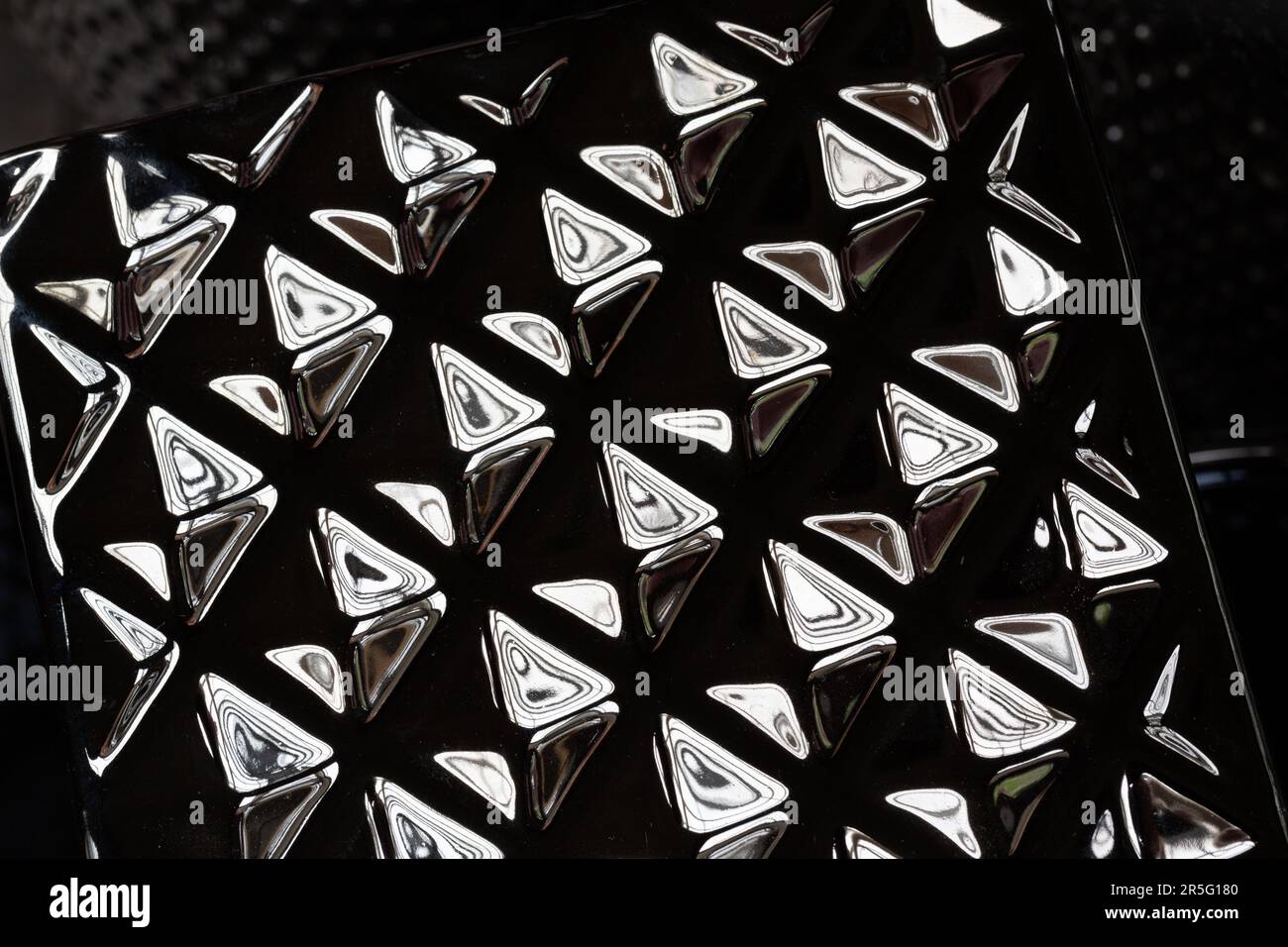 Grafische Elemente werden auf einem metallischen Quader reflektiert. Stockfoto