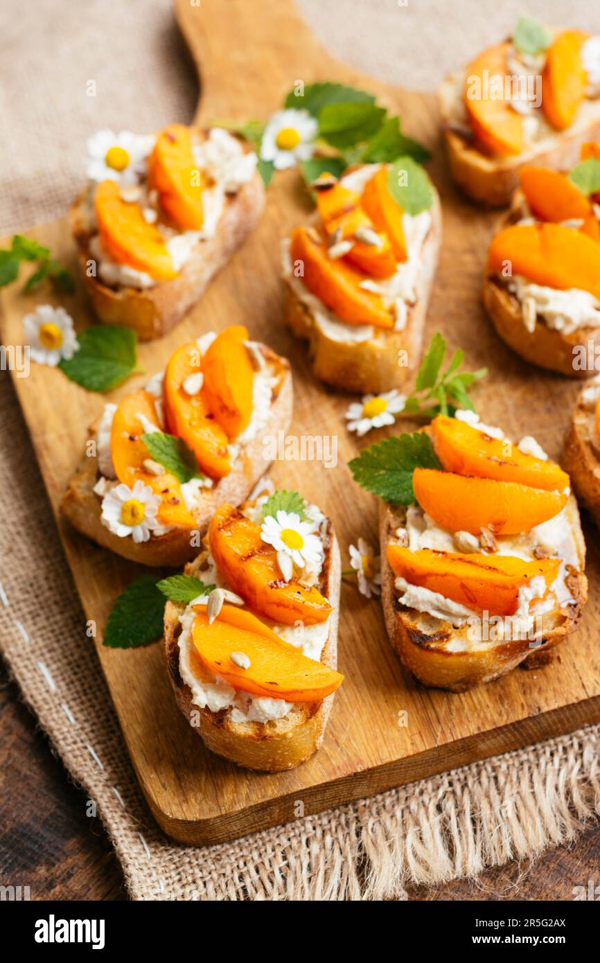 Schneidebrett mit hausgemachter Aprikose auf veganem Frischkäse-Bruschetta. Stockfoto