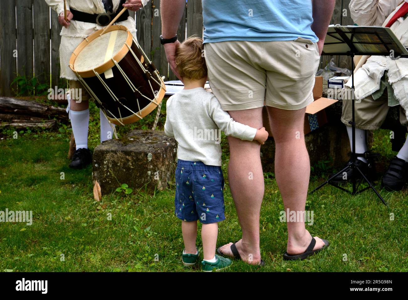 Ein Vater und sein junger Sohn hören sich ein Trommel- und Fifenkonzert bei einer lebendigen Geschichtsnachstellung in Abingdon, Virginia, an. Stockfoto