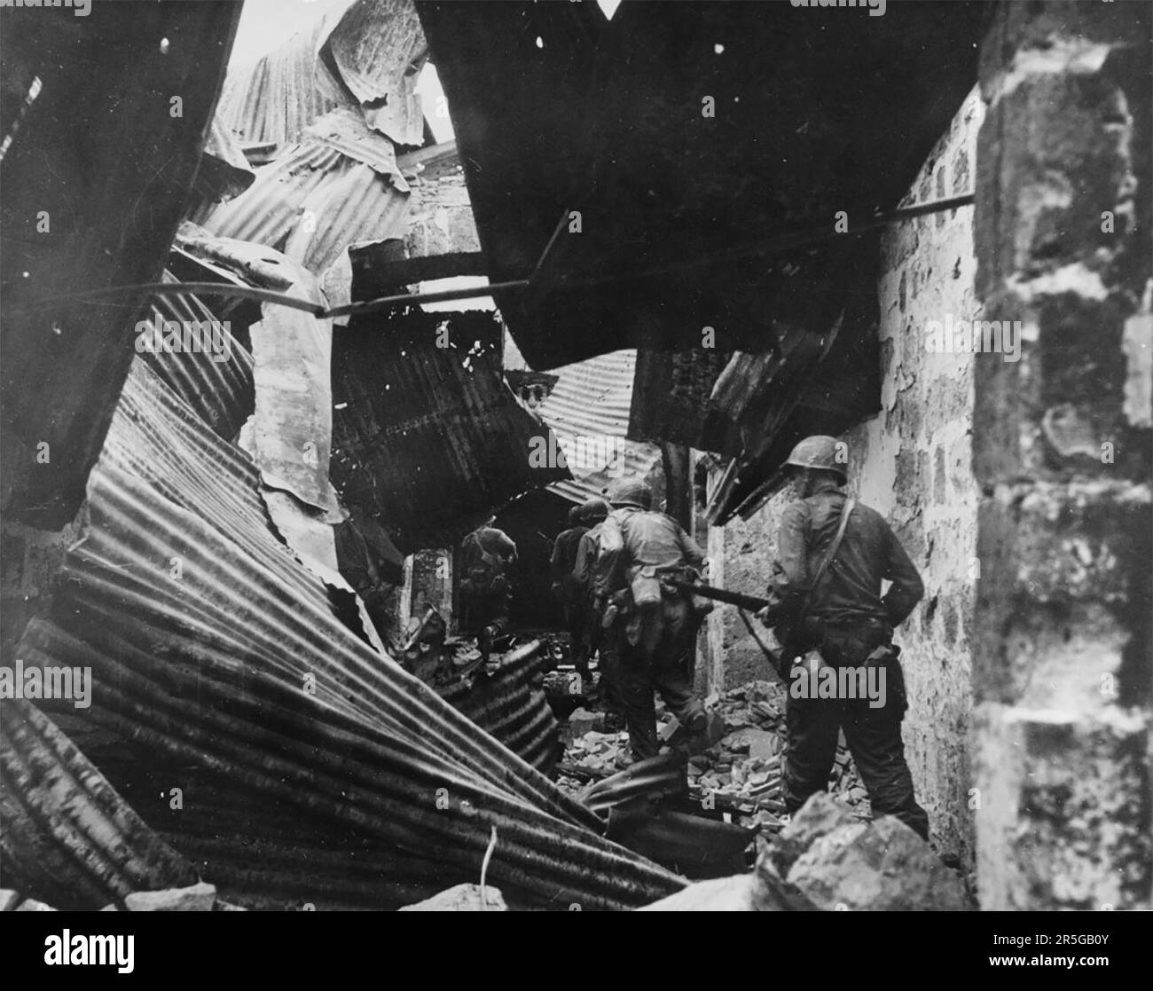 US-Infanteristen suchen nach Japanern in den Ruinen der ummauerten Stadt, aus der sie am 23. Februar 1945 Hunderte philippinischer Gefangene befreit hatten Stockfoto
