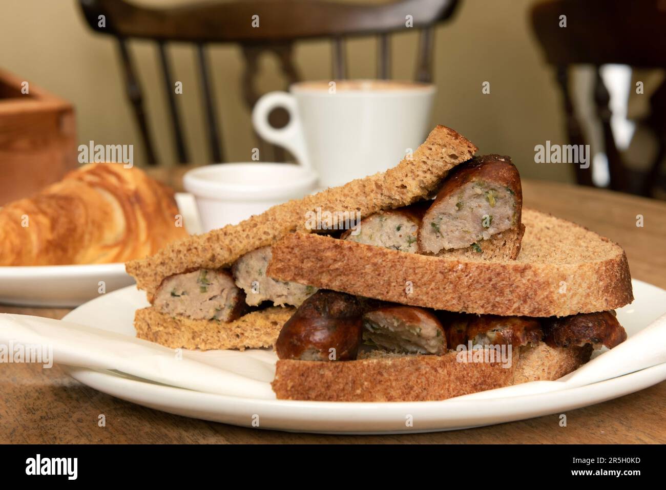 Würstchen-Sandwich, Croissant und Kaffee Stockfoto