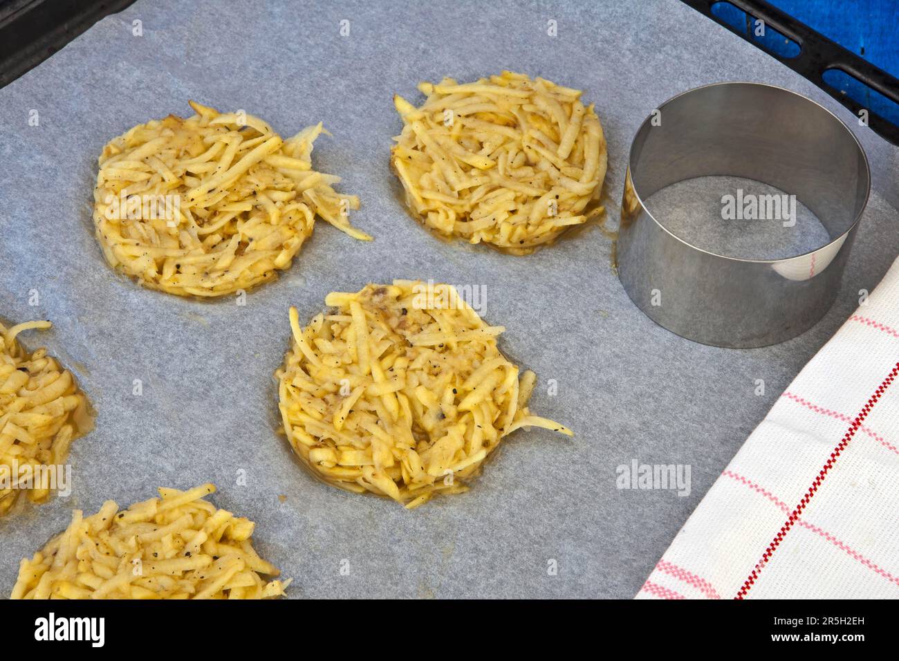 Geriebene Jackenkartoffeln, gewürzt, mit Ei gebunden, runde Form, Backblech Stockfoto