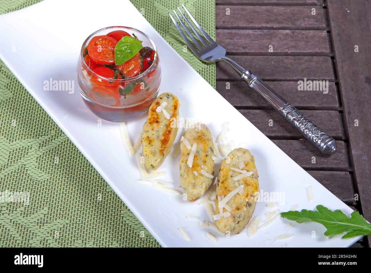 Hüttenkäse und Raketenknödel, mit gerösteten Tomaten und Parmesankäse, Hüttenkäse und Raketenknödeln, Gnocchi, Knödel, Parmesan Stockfoto