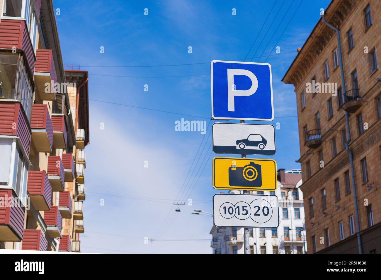 Städtische Parkvorschriften: Kostenpflichtige Parkplätze und Verkehrsschilder mit blauem Hintergrund Stockfoto