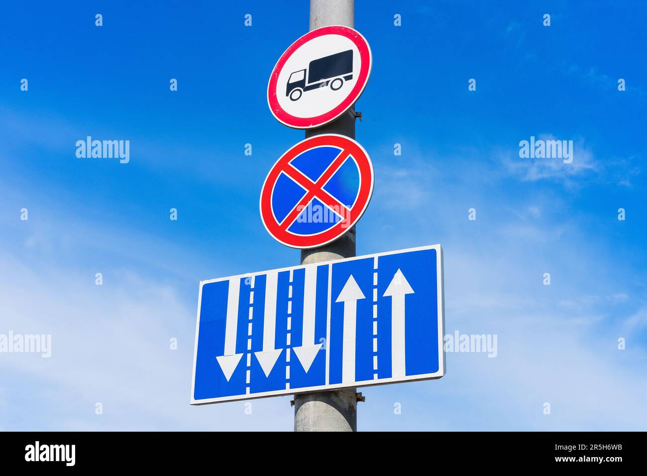 Ein Verkehrsschild, das das Parken von Fahrzeugen verbietet (rotes Kreuz auf blauem Kreis), mit einem zusätzlichen Schild, das die Bewegung von Lastwagen verbietet und die Fahrspur anzeigt Stockfoto