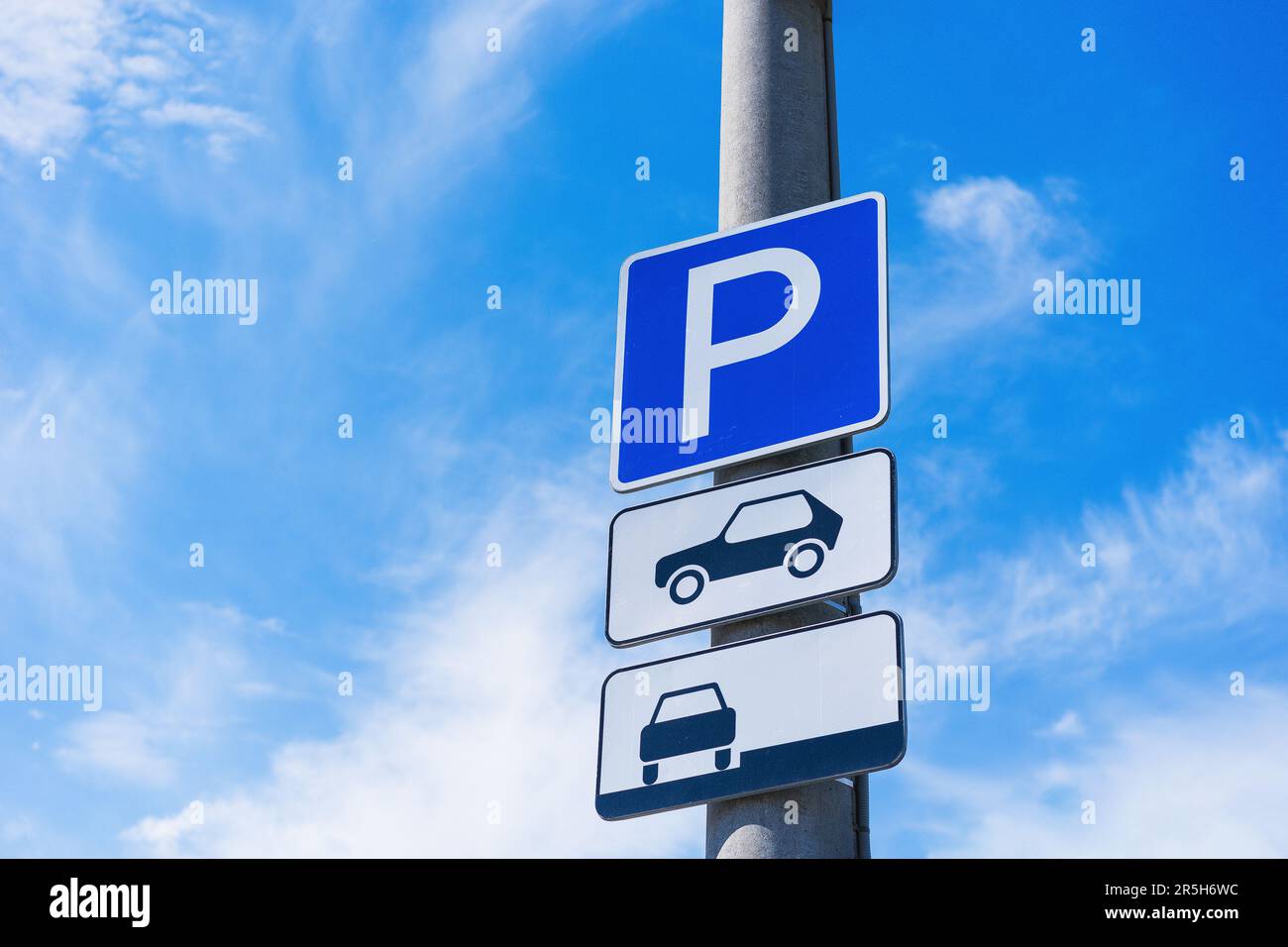 Parkschild für Personenkraftwagen mit Hinweis auf das Parken am Straßenrand auf einem Betonmast vor blauem Himmelshintergrund Stockfoto