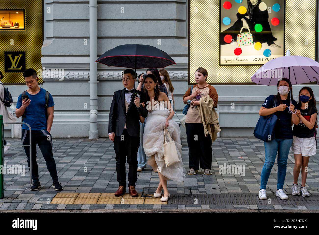 Ein frisch verheiratetes Paar wartet auf Cross the Street, Kowloon, Hongkong, China. Stockfoto