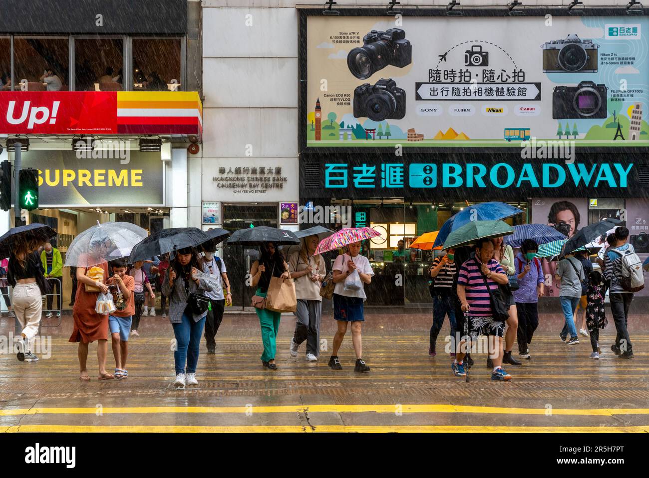 Gewöhnliche Leute aus Hongkong, die Während Eines Gewitters Eine Straße überqueren, Causeway Bay, Hongkong, China. Stockfoto