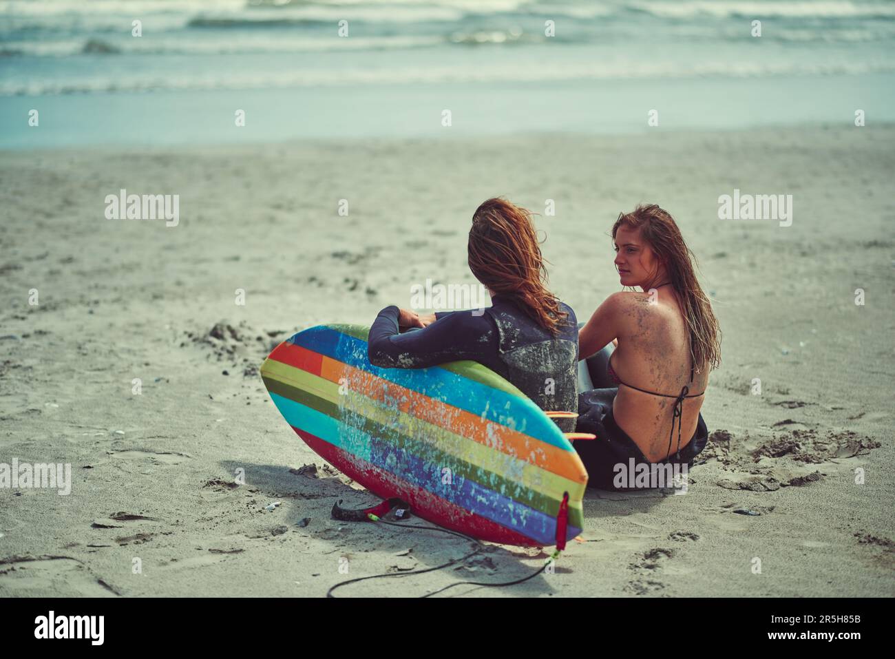 Surfen ist ein Erlebnis, das man am besten teilen kann. Ein junges Paar, das am Strand surft. Stockfoto