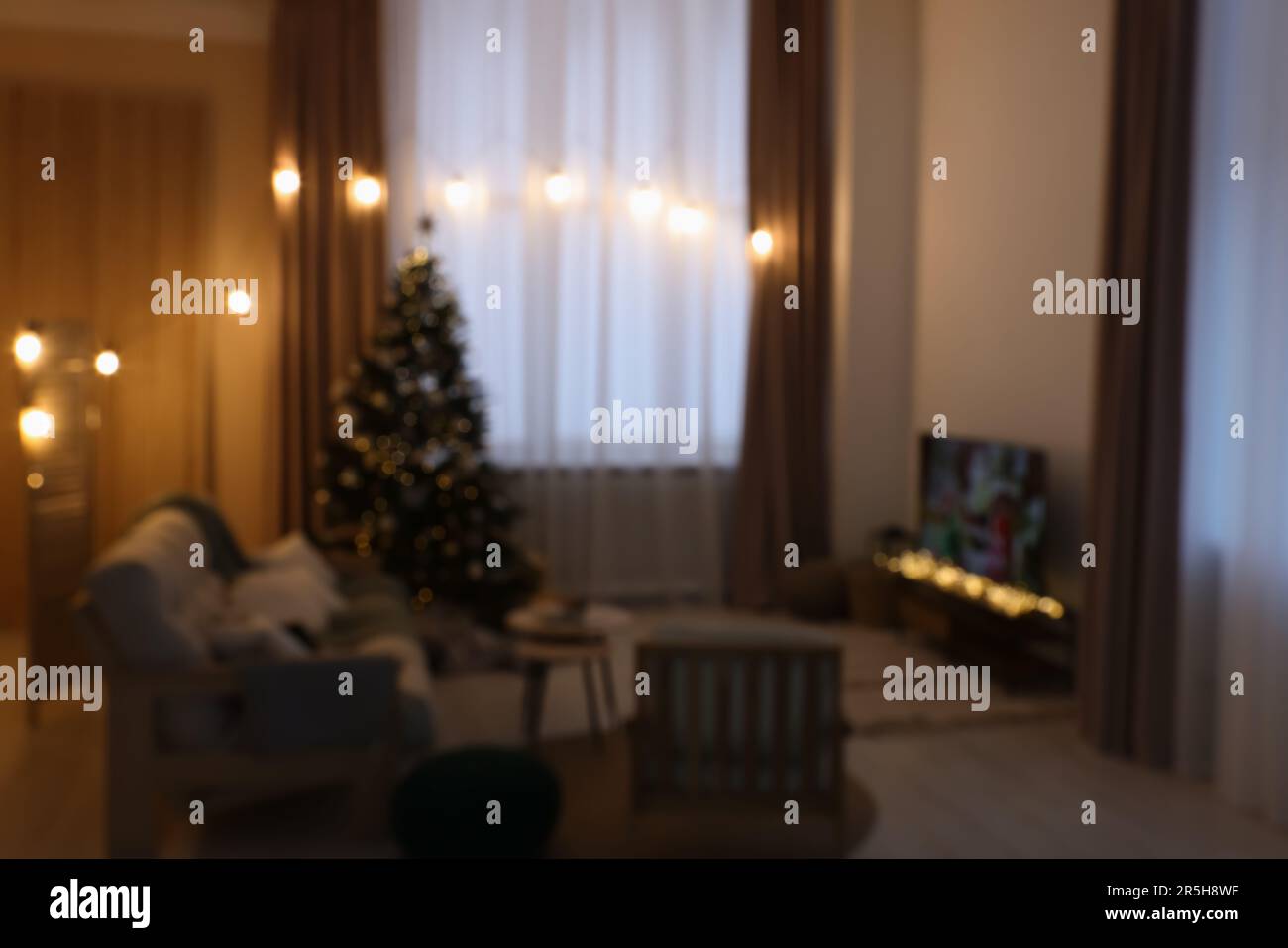 Fernseher, Möbel und Weihnachtsbaum in stilvollem Zimmer, verschwommener Blick Stockfoto