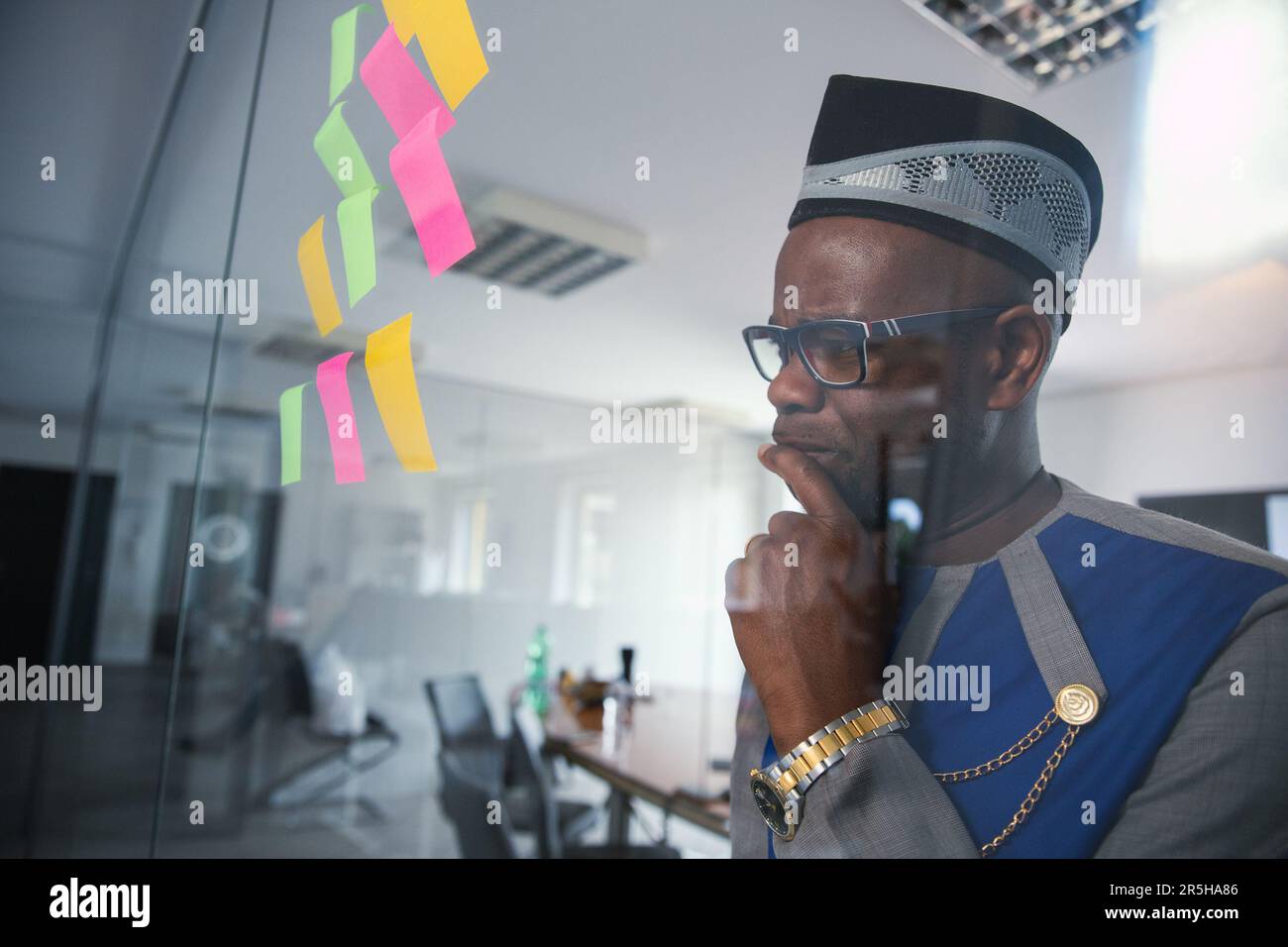 Ein afrikanischer Geschäftsmann sieht aufmerksam auf die Klebezettel an der Wand Stockfoto