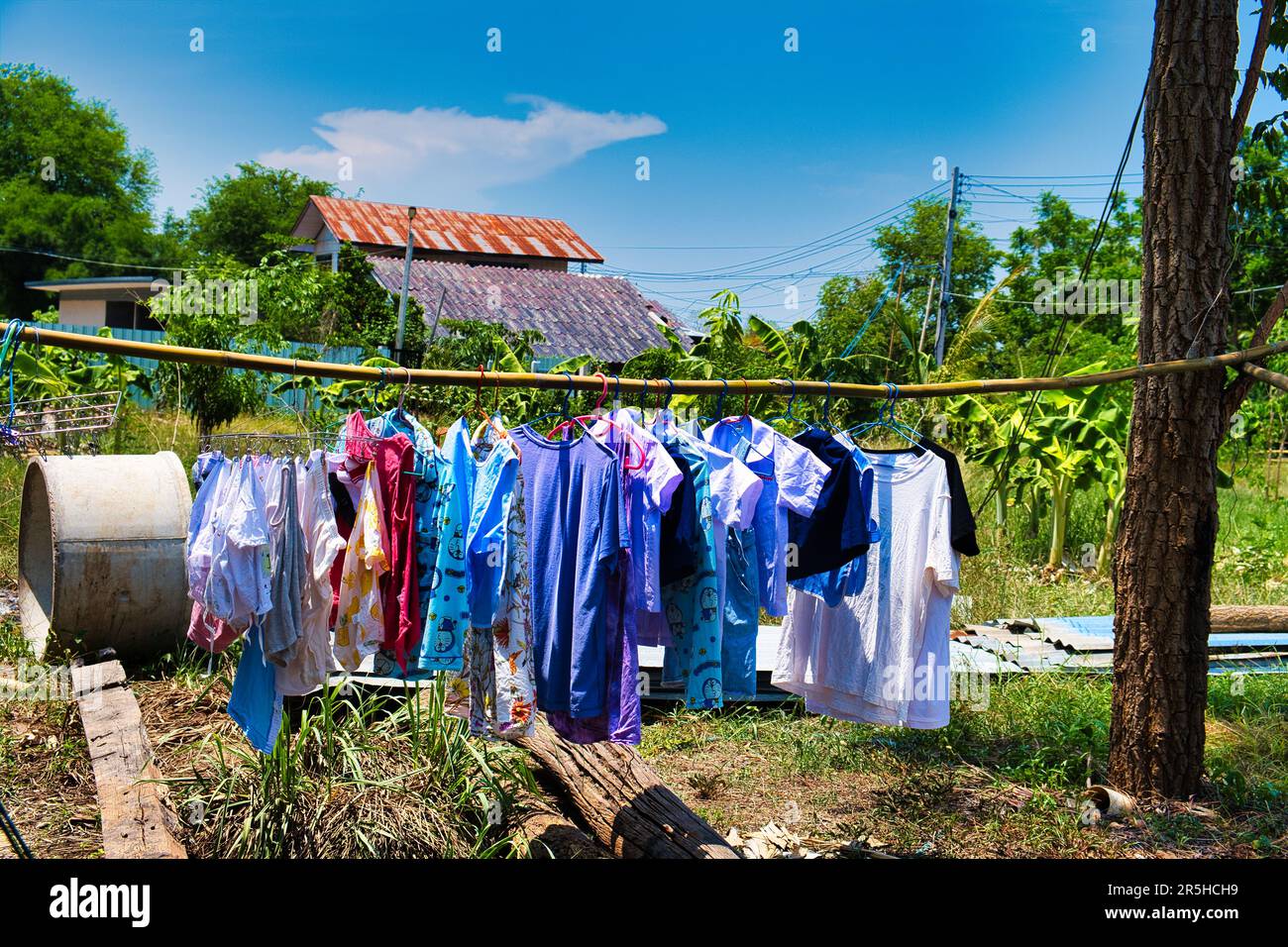 Wäsche hängt zum Trocknen an einer Bambusstange in einem Garten auf einem Bauernhof in Zentral-Thailand Stockfoto