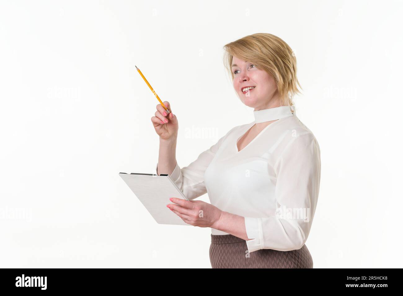 Porträt glückliche, reife Geschäftsfrau, die das Klemmbrett hält und mit dem Finger mit einem Bleistift nach oben zeigt. Weiße ethnische Blondine 49 Jahre alt Stockfoto