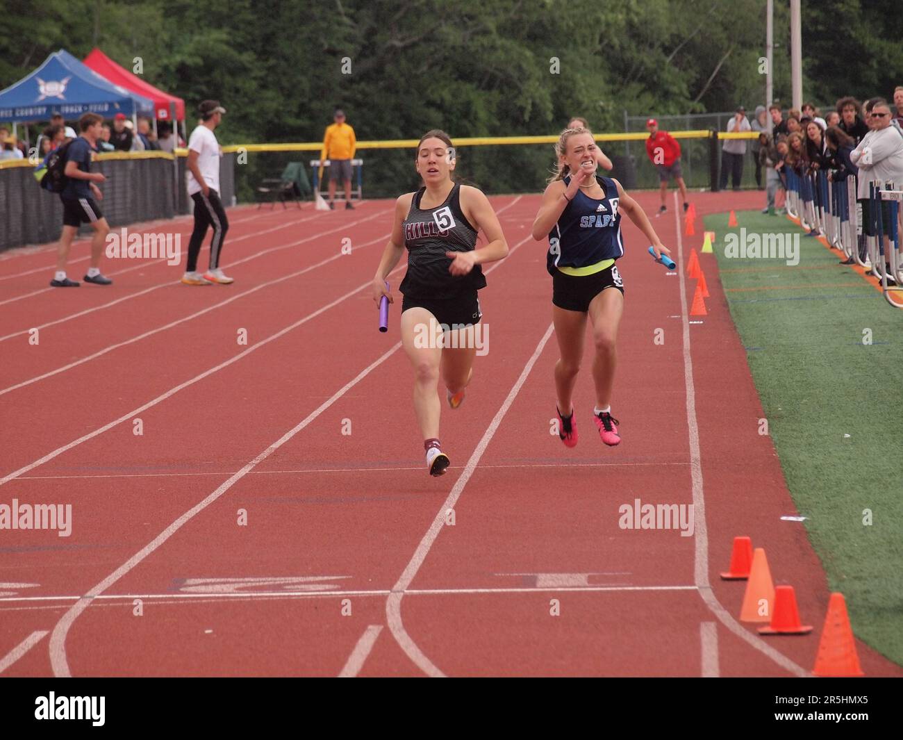 Highschool-Sprinter kämpfen um ein 400 Meter langes Staffelrennen. Entschlossenheit und Stärke werden auf den Flächen der Mitbewerber angegeben. Stockfoto