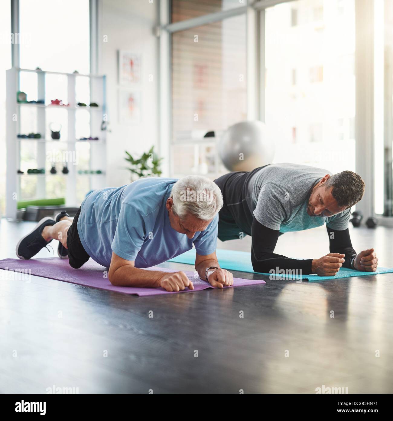 Werden fitter und flexibler. Ein junger männlicher Physiotherapeut, der einem älteren Patienten bei der Genesung hilft. Stockfoto