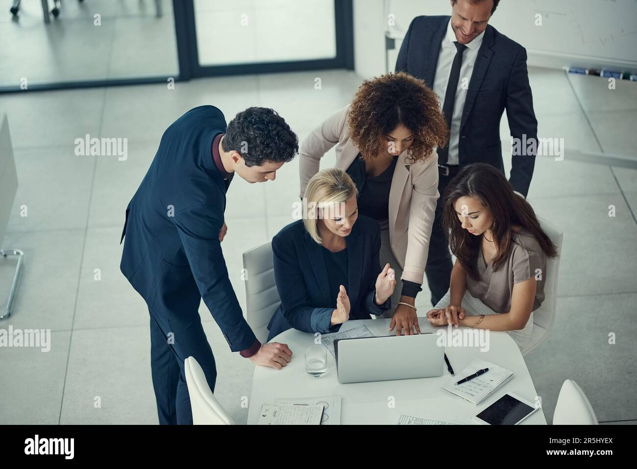 Fortschritte bei jedem Meeting. Eine Gruppe von Kollegen, die während einer Besprechung in einem modernen Büro gemeinsam ein Notebook verwenden. Stockfoto