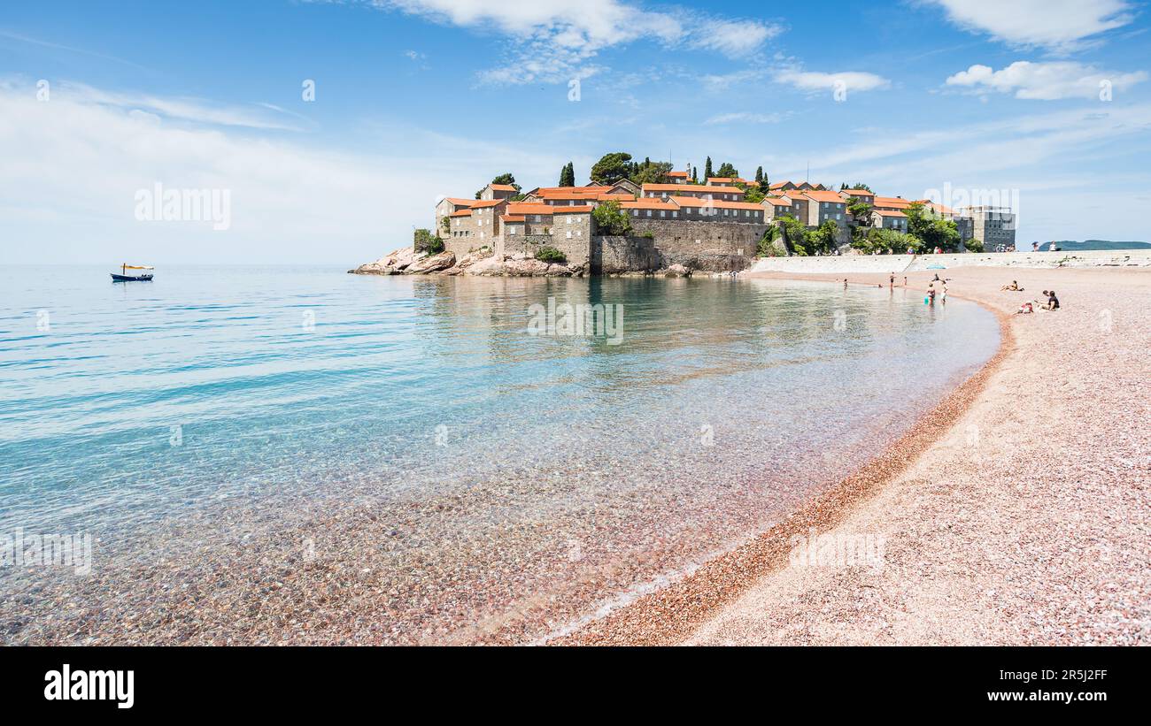 Winken Sie sanft gegen den Strand am Sveti Stefan an an der Küste Montenegros im Mai 2023. Stockfoto