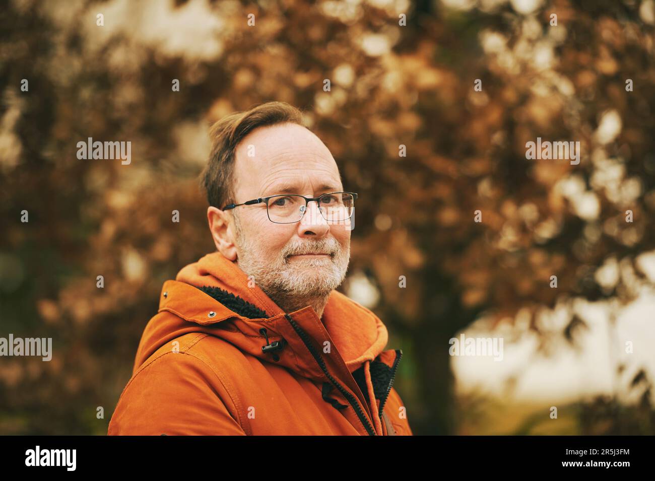 Herbstporträt eines Mannes mittleren Alters mit orangefarbener Jacke Stockfoto