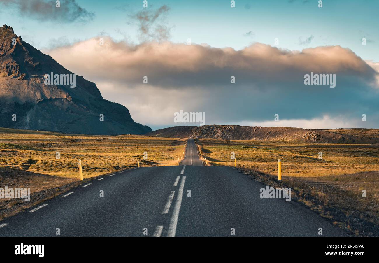 Malerische asphaltierte Straße mit Sonnenlicht und Blick auf die Berge im Sommer Islands Stockfoto