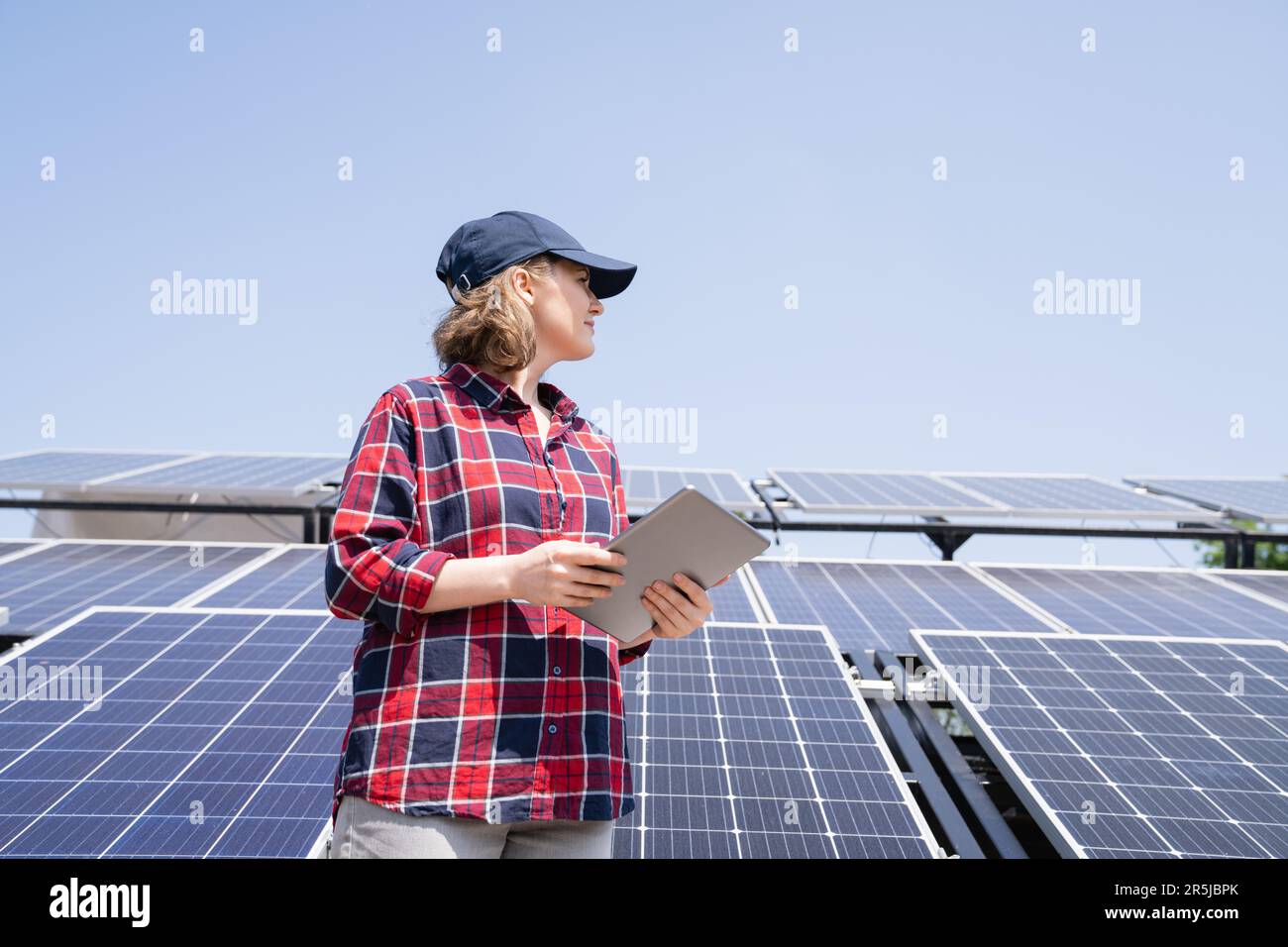 Frau mit digitalem Tablet vor dem Hintergrund eines mobilen Solarkraftwerks. Stockfoto