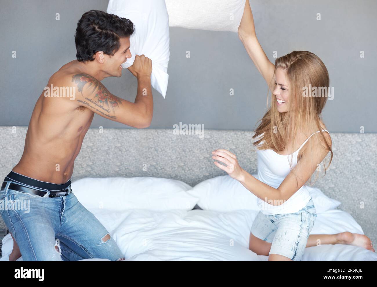 Den Spaß in ihrer Beziehung zu behalten. Ein verspieltes Paar, das sich auf dem Bett mit Kissen prügelt. Stockfoto