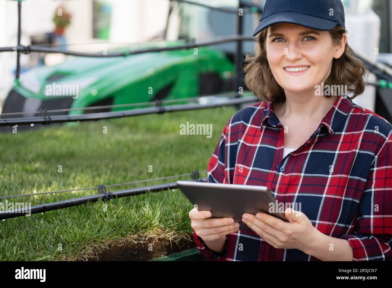 Landwirtin mit digitalem Tablet neben einem Rohr zur Tropfbewässerung. Stockfoto