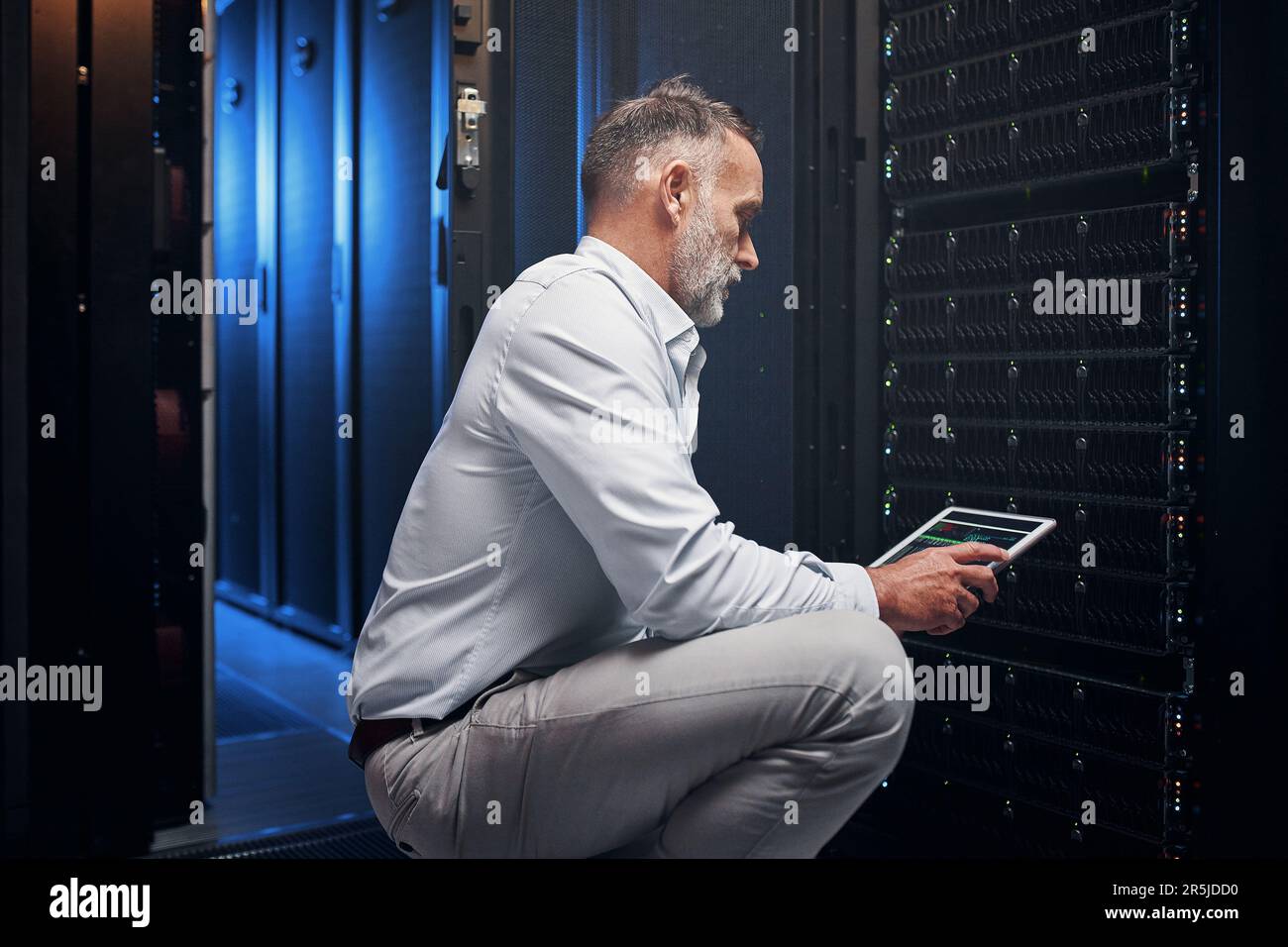 Die schnellste Glasfaserinstallation in der Branche. Ein erwachsener Mann, der ein digitales Tablet verwendet, während er in einem Serverraum arbeitet. Stockfoto