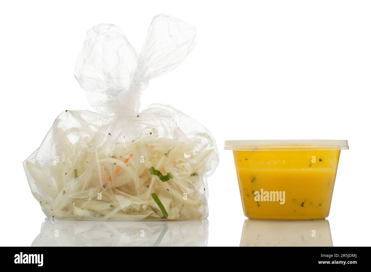 Bei einem indischen Essen zum Mitnehmen wurden Sachen hinzugefügt (aber nicht immer gegessen). Gehackte Zwiebeln in einer Plastiktüte und gelbe Dippsoße. Stockfoto