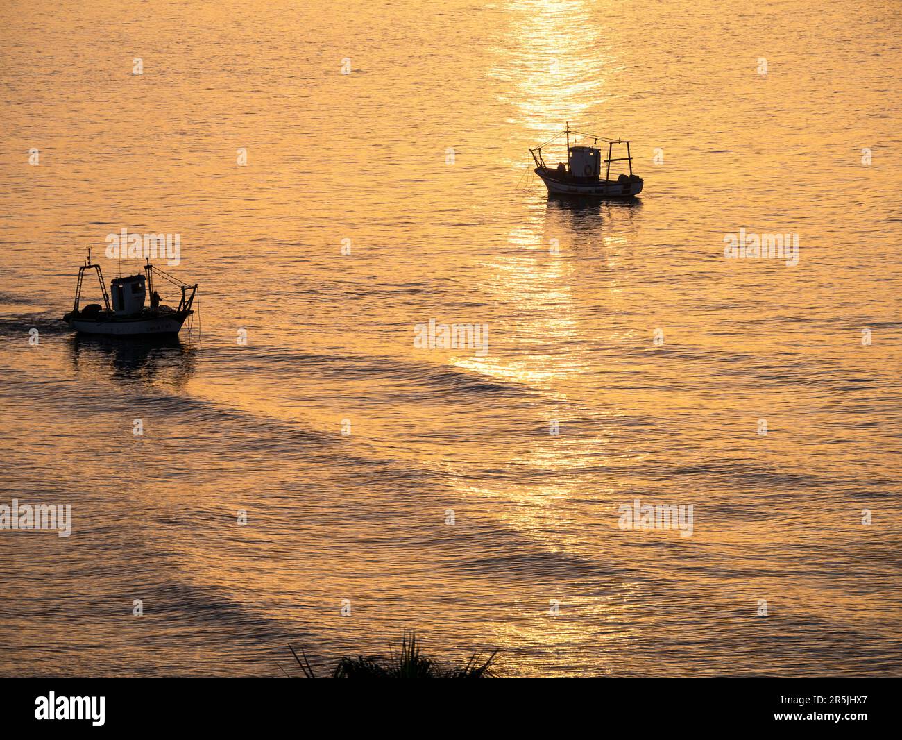 Fischerboot bei Sonnenaufgang vor dem Strand in Fuengirola Spanien. Dieses Boot kam jeden Morgen unseres Aufenthalts an der Costa del Sol. Stockfoto