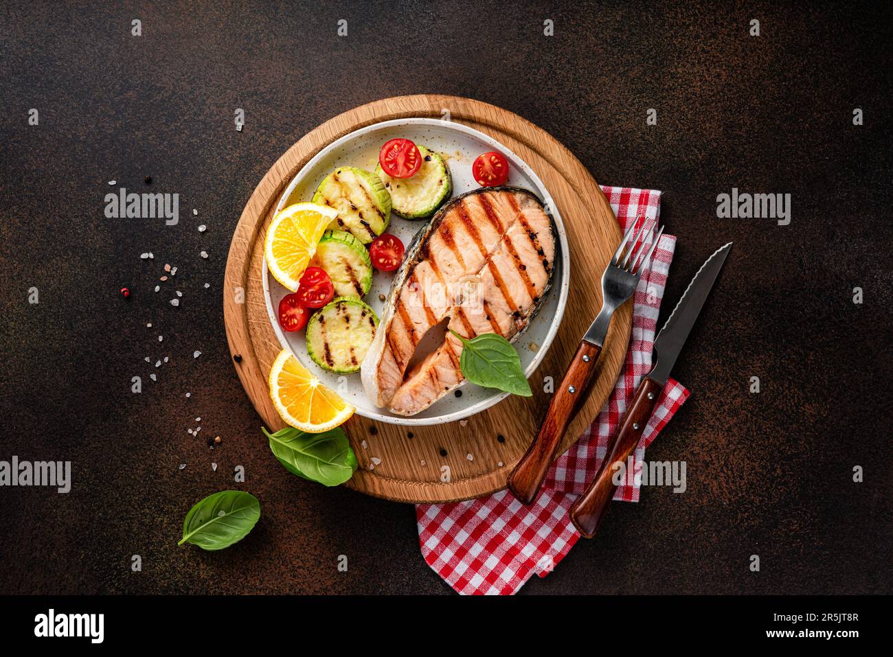 Gegrillte Lachssteaks mit Gewürzen, Zitronen und gegrillten Zucchini auf Holzbrett. Blick von oben auf gebratenen Fisch. Keto-Rezept. Stockfoto