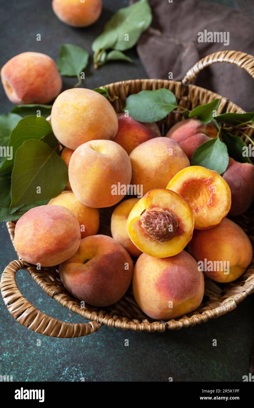 Erntehintergrund. Bio-Früchte. Bauernmarkt. Korb reifer Pfirsiche auf einem Steintisch. Stockfoto