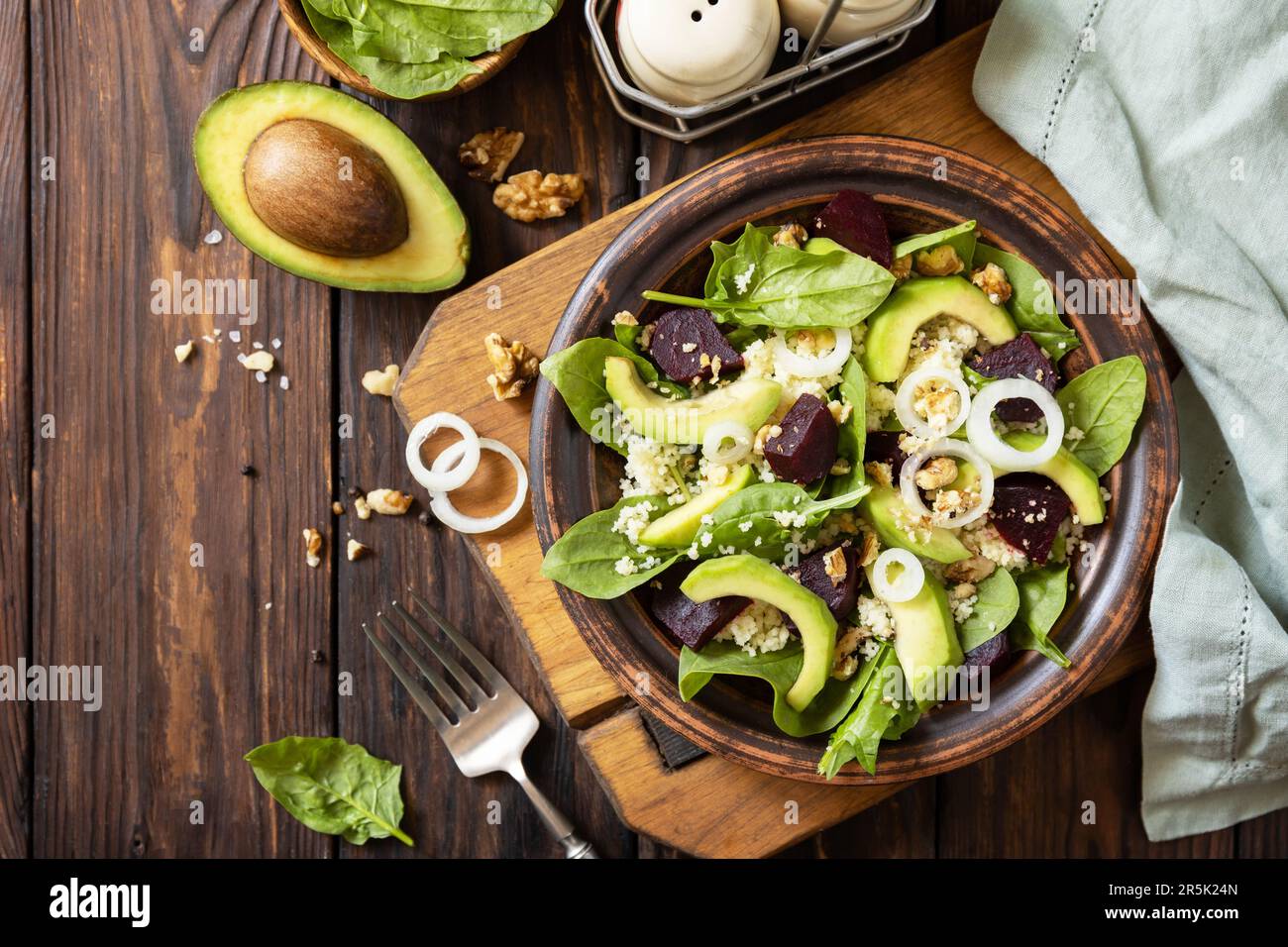 Couscous mit Avocado, Rüben, grünen Bohnen und Spinat auf einem rustikalen Holztisch. Veganes Essen. Blick von oben. Speicherplatz kopieren. Stockfoto
