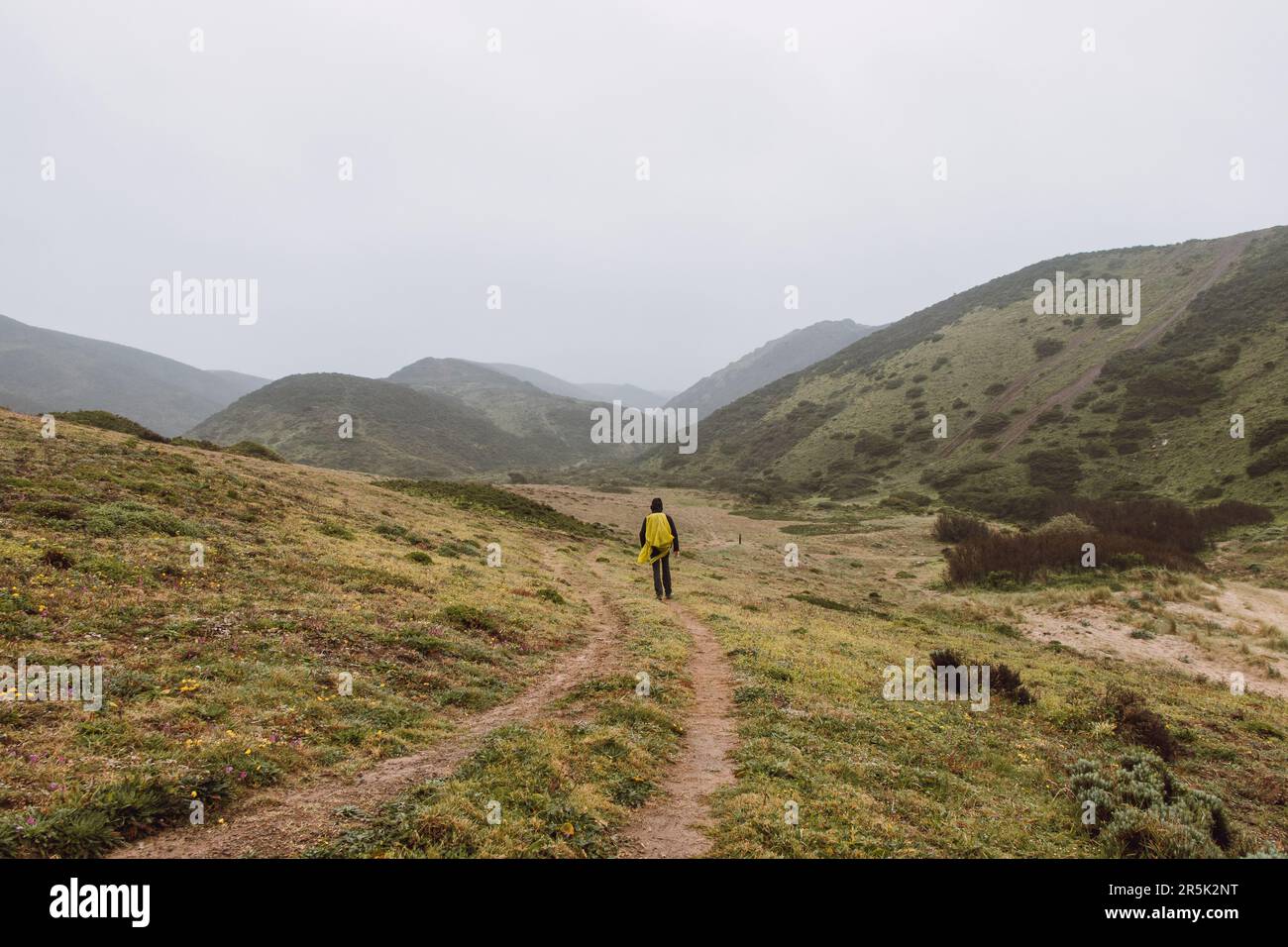 Wandern bei starkem Regen und Tragen einer Regenjacke entlang des Fisherman Trail im südlichen Teil Portugals bei Regenwetter auf dem Weg nach Cape St. Vic Stockfoto