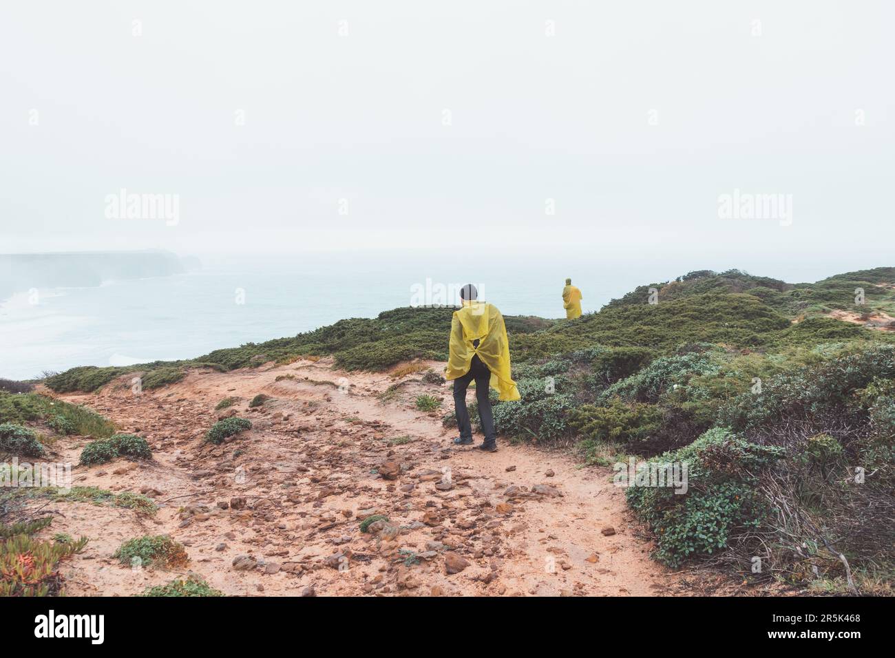Wandern bei starkem Regen und Tragen einer Regenjacke entlang des Fisherman Trail im südlichen Teil Portugals bei Regenwetter auf dem Weg nach Cape St. Vic Stockfoto