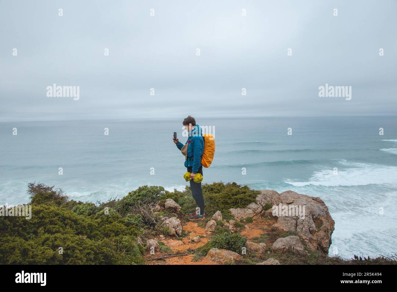 Ein Abenteurer, der auf dem Fisherman Trail in der Algarve von Portugal spaziert, macht Fotos vom Ozean, der während des Regenwetters zum Leben erwacht ist Stockfoto